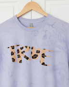 Amethyst Freebrd tie-dye shirt with 'TRUE' in cheetah print on a wooden hanger against a white wall.