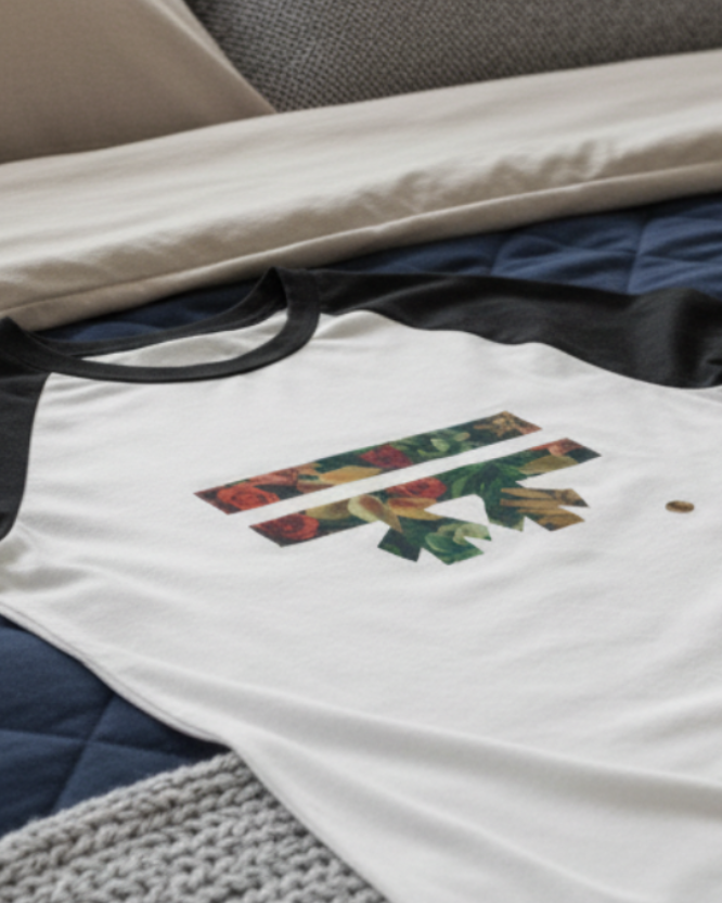 White t-shirt with Freebrd Autumn floral logo on a bed