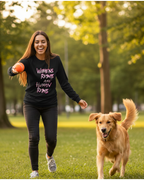 Woman running with a dog in a park wearing a black Freebrd women's rights long sleeve shirt