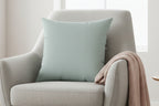 Cool Silver Faux Suede Square Pillow on a sofa chair with a blanket.