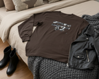 Brown Freebrd retro camera designed t-shirt with graphic design on a bed with black leather jacket and boots.