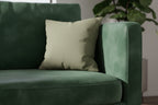 Dark Neutral Wood Colored Faux Suede  pillow on a green textured sofa with a blurred green plant in the background