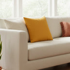 Dixie Florida Orange Faux Suede Square Pillow on a beige couch. 