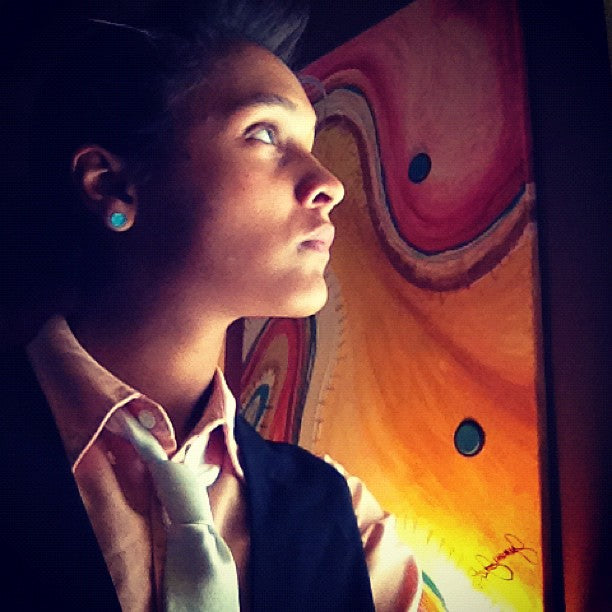Arkansas Artist Jasmine Jackson looking up at her colorful abstract painting