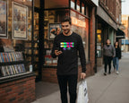 Man walking on a sidewalk in front of a movie theater with a colorful Freebrd graphic on his black shirt.