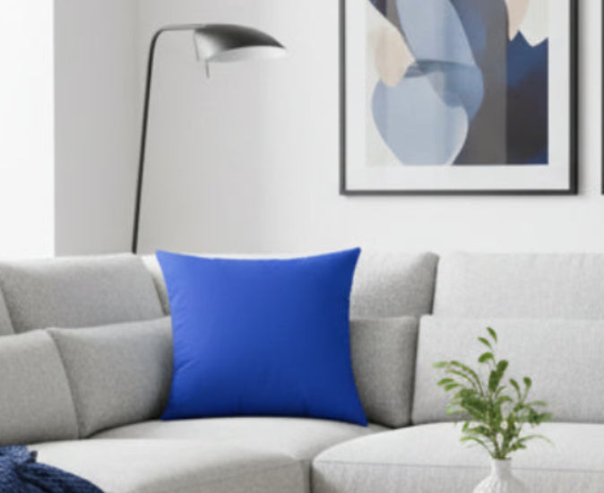 Gray sofa with a Funky Blue Luxury Faux Suede Square Pillow, floor lamp, and abstract art in a living room.