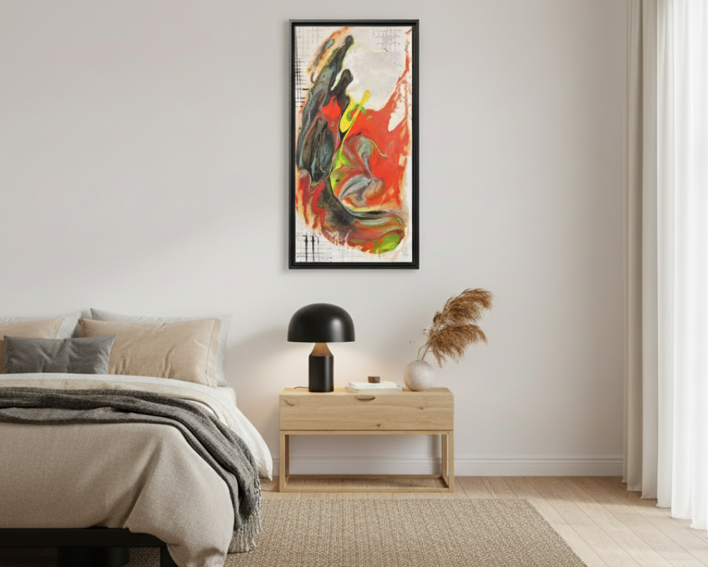 A bedroom lifestyle view of the “Grid Riser Rhino” Abstract Framed Art by FREEBRD on a 1.25” canvas with a 16" x 32” Vertical frame, showcasing vibrant orange, red, green and black acrylic textures with hints of vivid yellow, coral and gold, framed in an espresso wood FSC certified frame hanging above a wooden nightstand with a lamp and accent decor. 