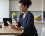 Woman sitting at a kitchen table using a smartphone and holding a colorful Freebrd designed mug.