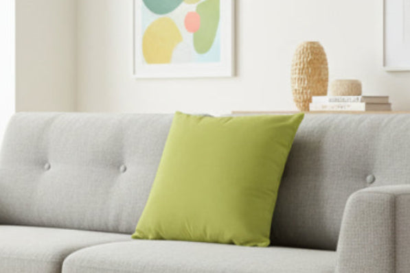 Gray sofa with an Orchid Green Luxury Faux Suede Pillow in a living room with abstract art on the wall.
