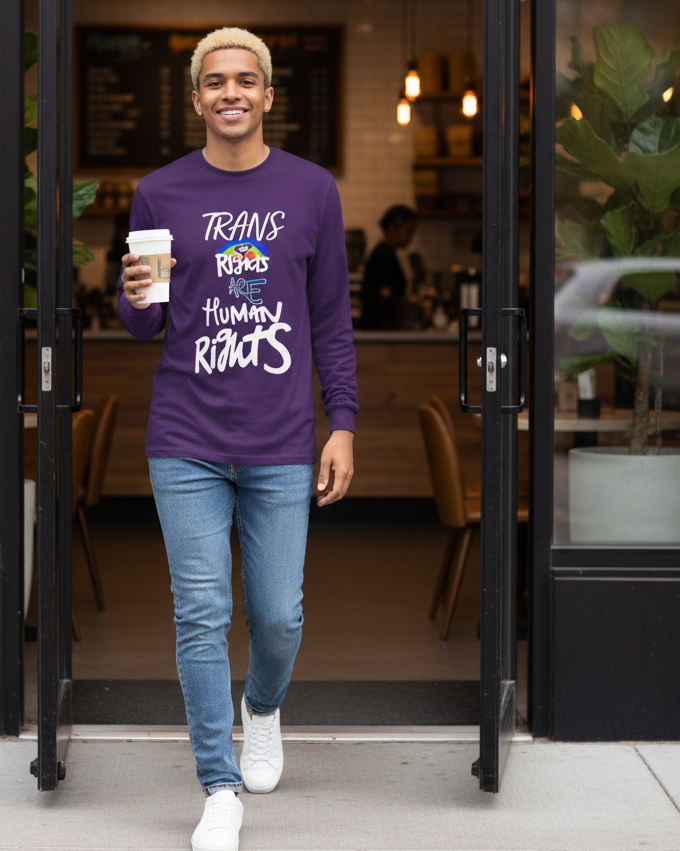 Person wearing a Freebrd designed purple shirt with a positive message, holding a coffee cup, standing in a doorway.