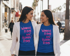 Two women wearing blue Freebrd Women's Rights t-shirts with pink text on a city street.