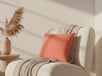 Beige armchair with a Salmon Pink Faux Suede Square Pillow and a vase with pampas grass on a wooden side table.