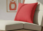 Traditional Red Faux Suede Square Pilloon a beige sofa with a blurred painting in the background