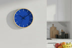 Modern Minimal Blue Silent Wall Clock with wooden frame on a white wall in a kitchen setting.
