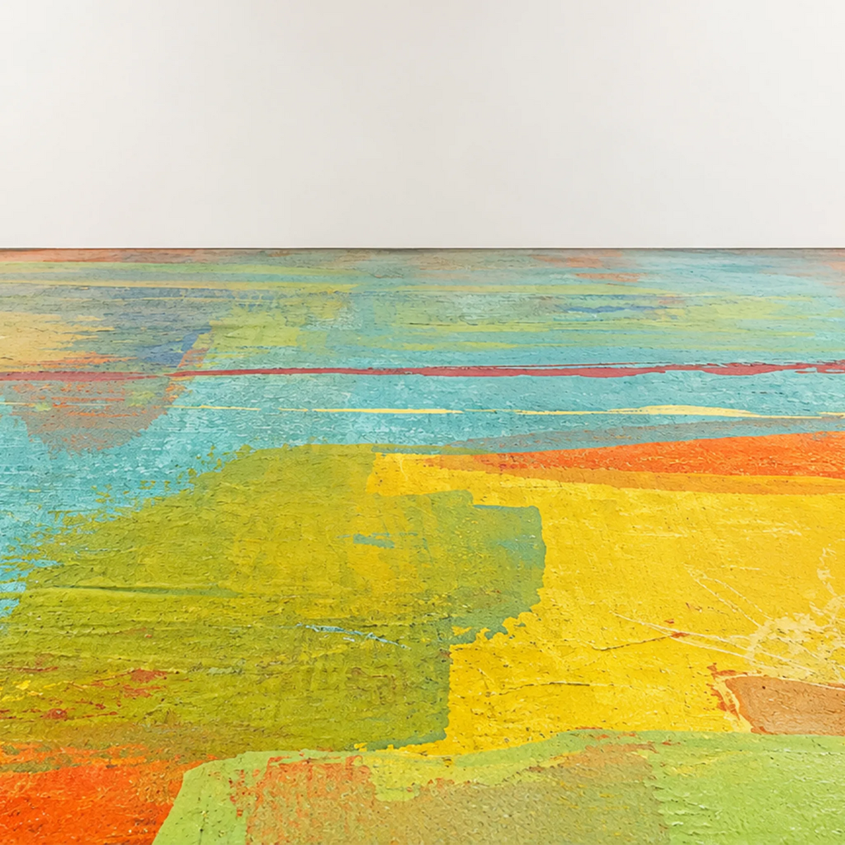 Painted floor with layered aqua, lime green, yellow, orange, and red marks receding toward a plain off-white wall.