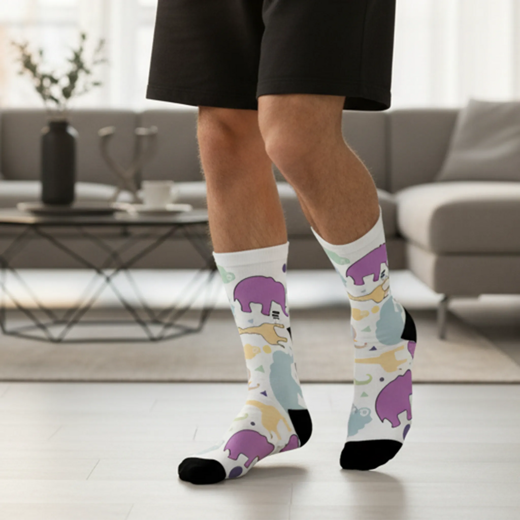 Animal Clouds Cushioned Mid-calf Socks. Featuring vibrant giraffe and elephant cloud prints in playful sea green, purple, and yellow colors with a black toe and heel being worn by a man.