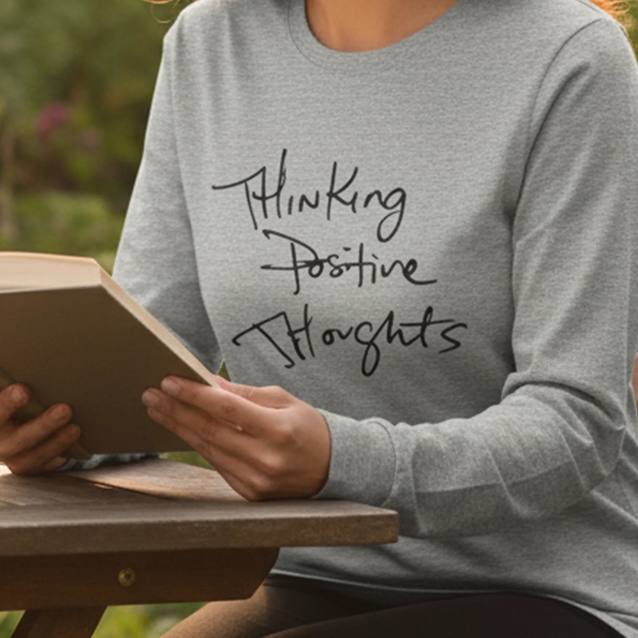 Athletic Heather Bella Thinking Positive Thoughts long sleeve tee, outdoor reading lifestyle front view.