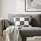 Atomic grey checkered lumbar pillow styled on a couch in a modern living room. 