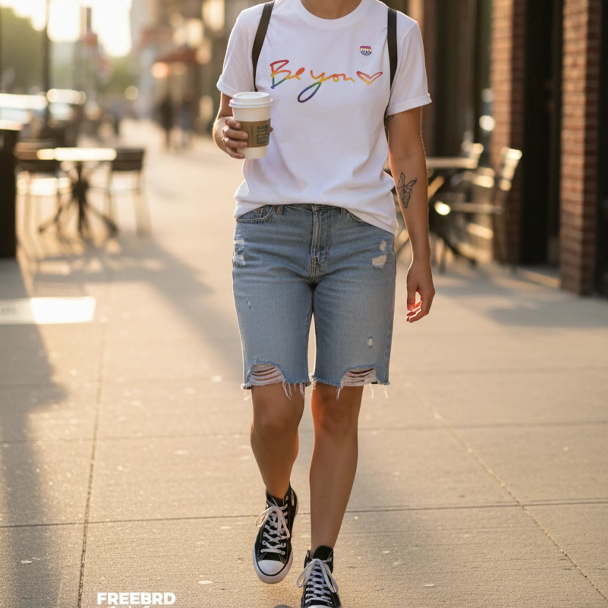 Be You rainbow script essential t-shirt, white, rainbow Be You heart graphic, golden hour street lifestyle, FREEBRD Pride Gear.
