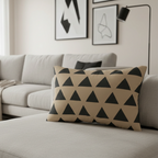 Beige black geometric triangle lumbar pillow styled on a couch in a modern living room.