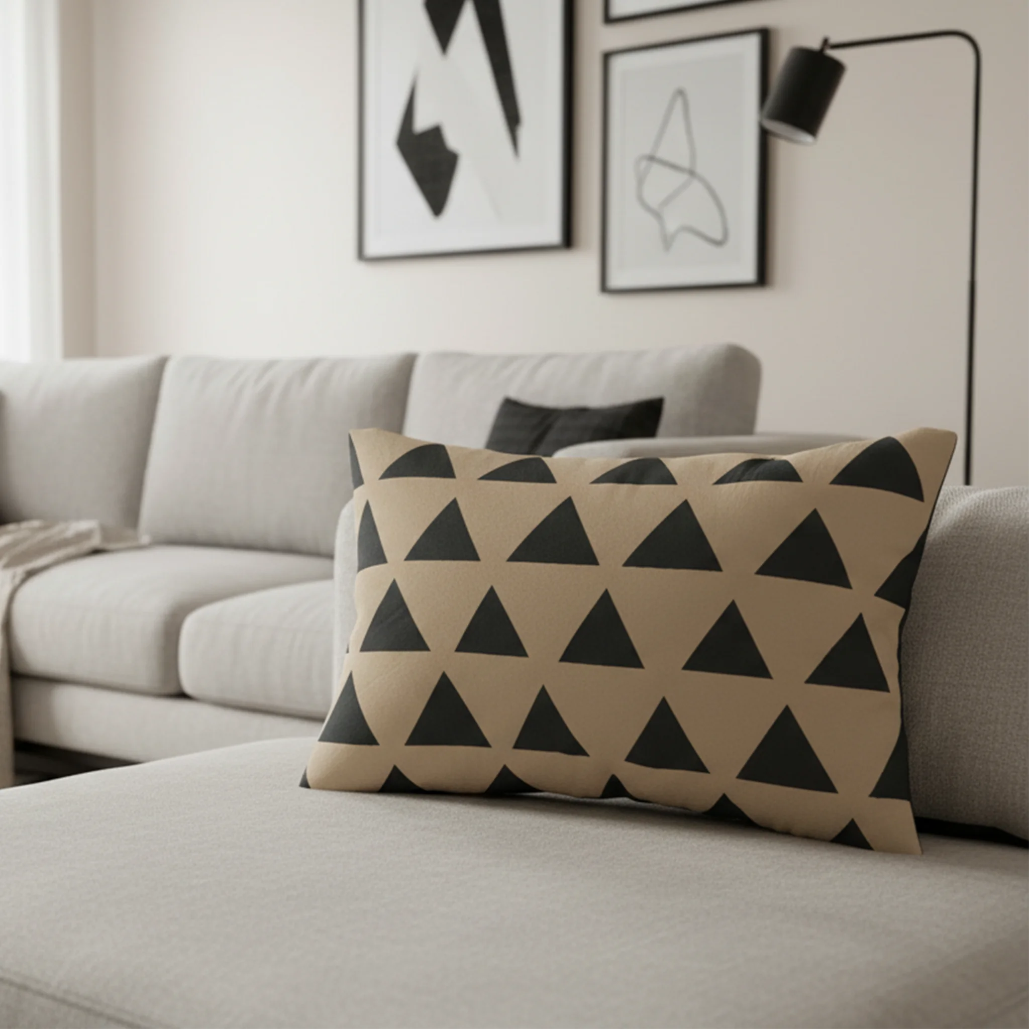 Beige black geometric triangle lumbar pillow styled on a couch in a modern living room.