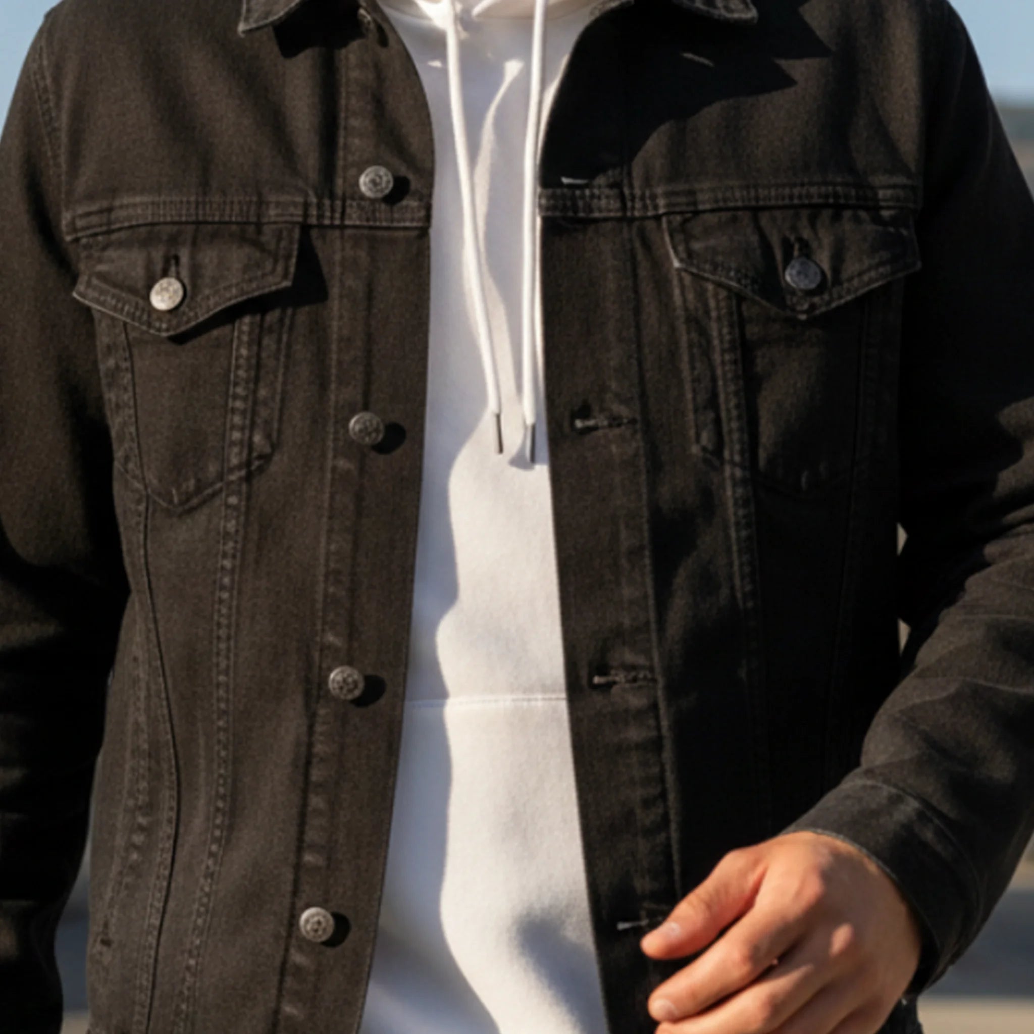 Black Denim trucker jacket, embroidered logo sleeve styled with a white hoodie, lifestyle view.