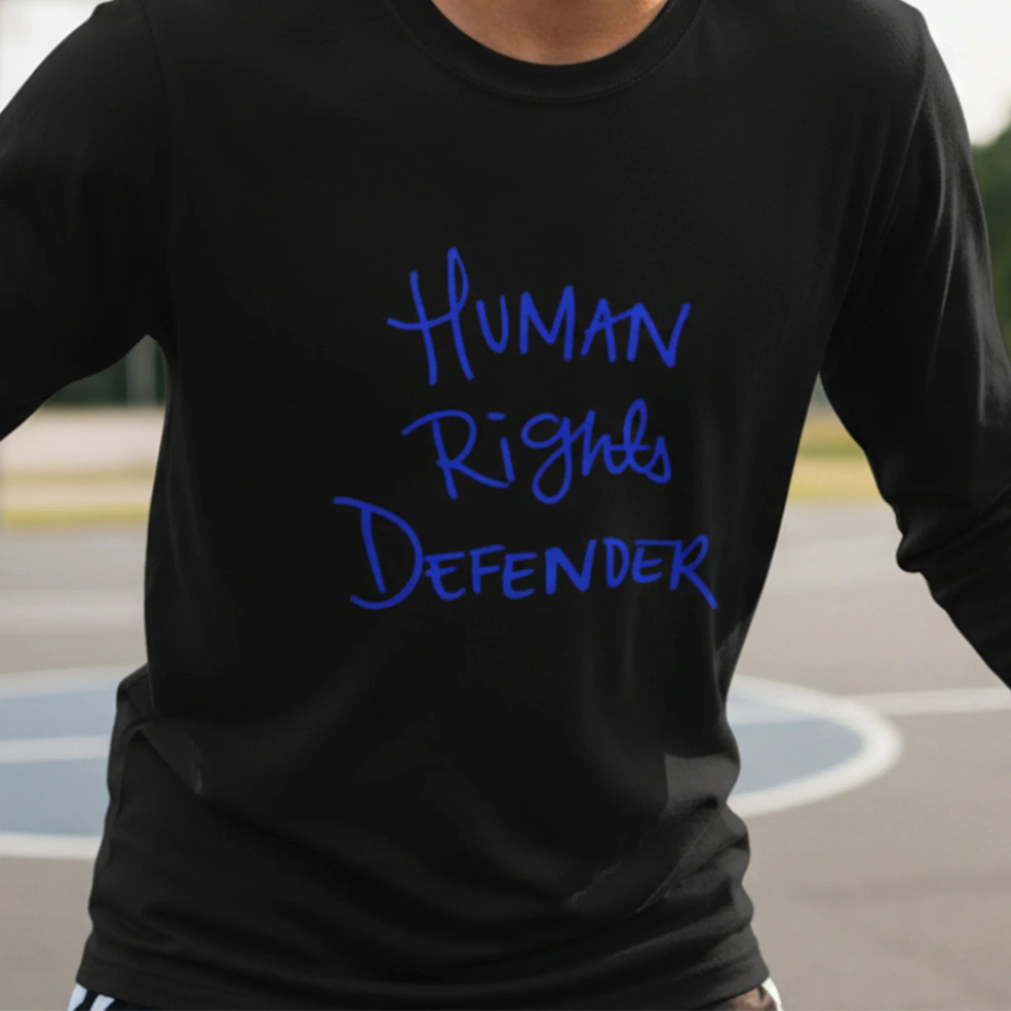 Black Human Rights Defender long sleeve tee, royal blue graphic, outdoor lifestyle front view.
