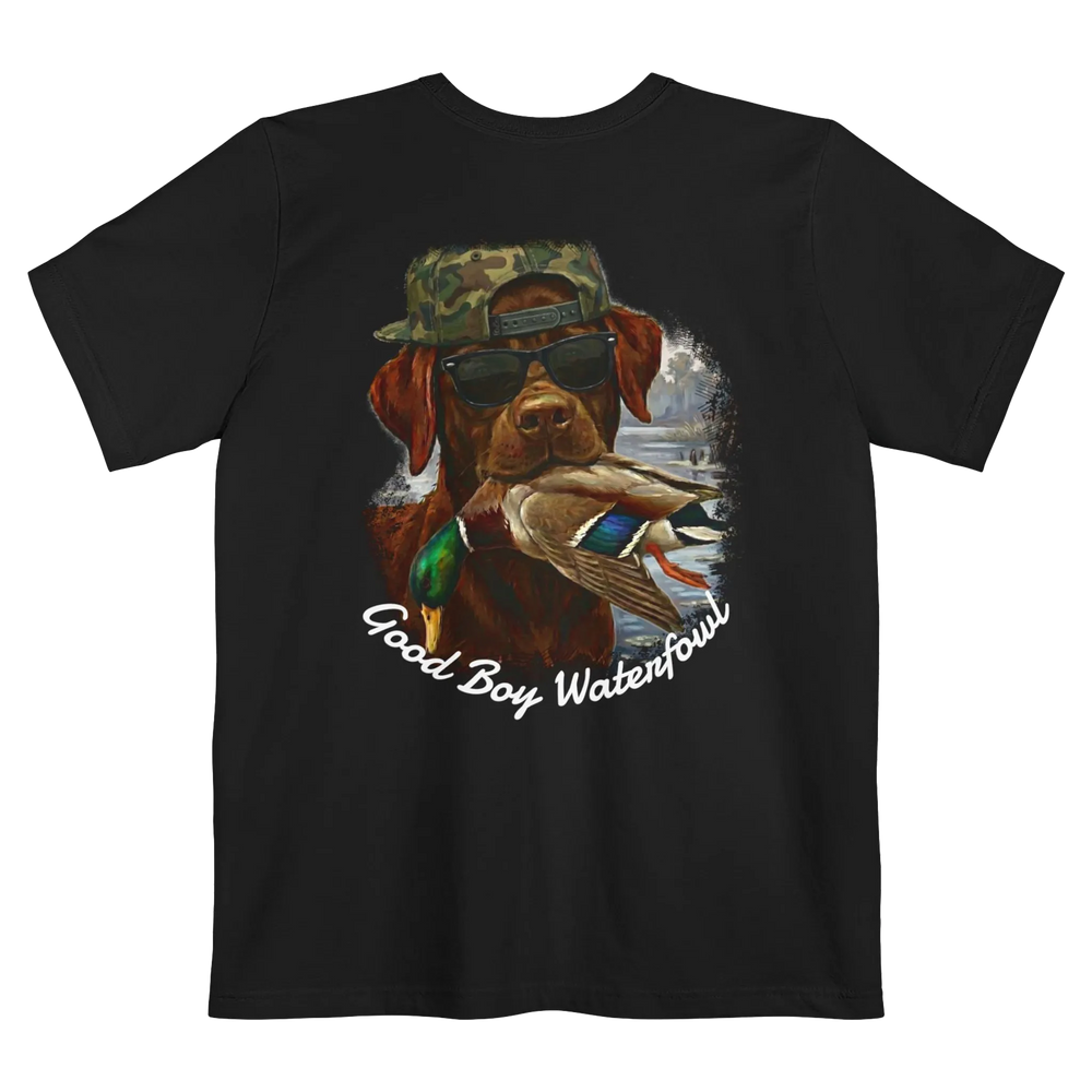 A black t-shirt featuring the Good Boy Waterfowl graphic of a chocolate Labrador wearing sunglasses and a camo snapback, holding a mallard duck, with a watercolor outdoor scene and 'Good Boy Waterfowl' script below.