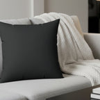 Carbon fiber faux suede pillow styled on sofa, dark charcoal minimalist home decor.