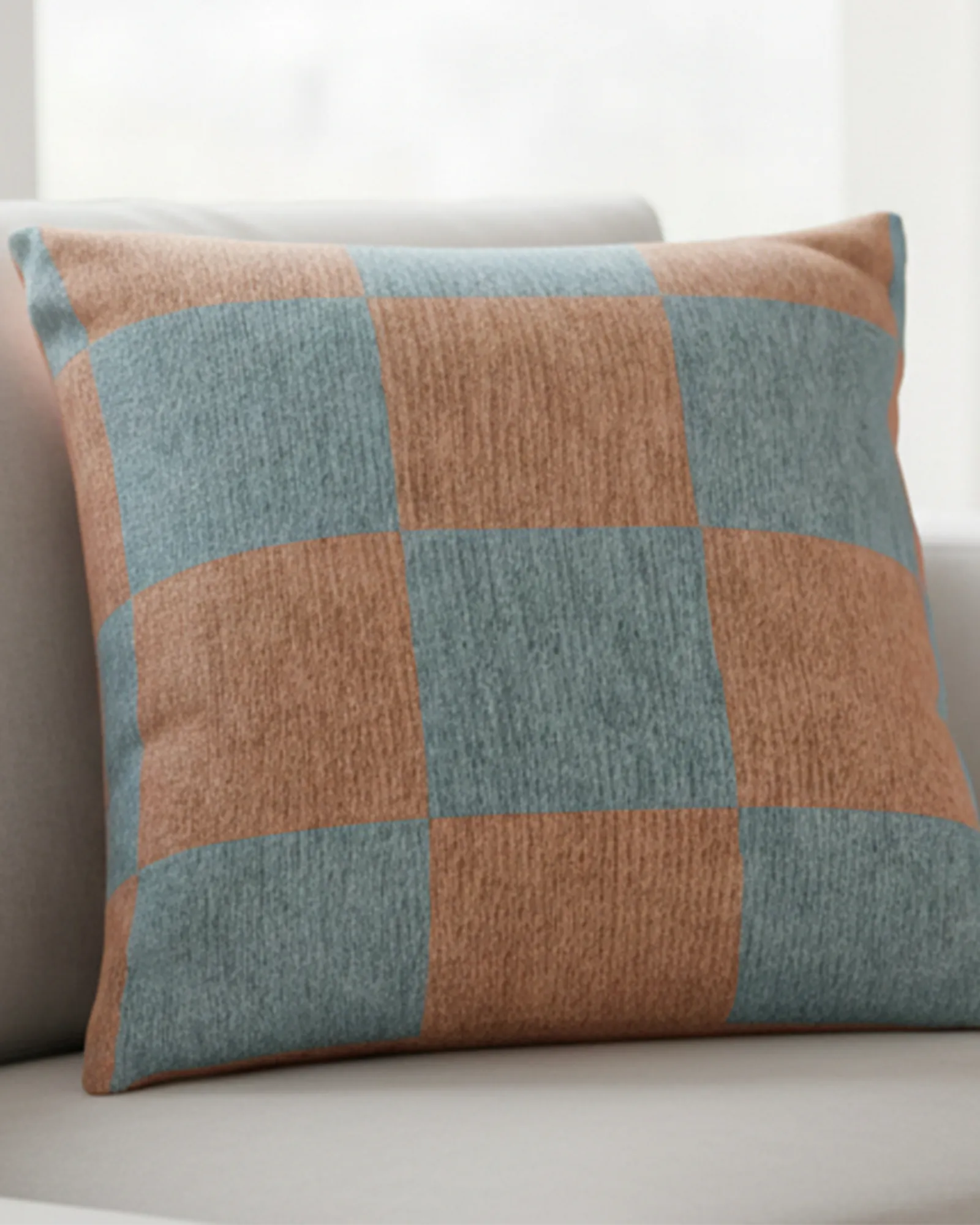 A preview of the Danish Blue Vintage Salmon Checker Woven Pillow showing danish blue checker squares on a salmon red background on a couch.