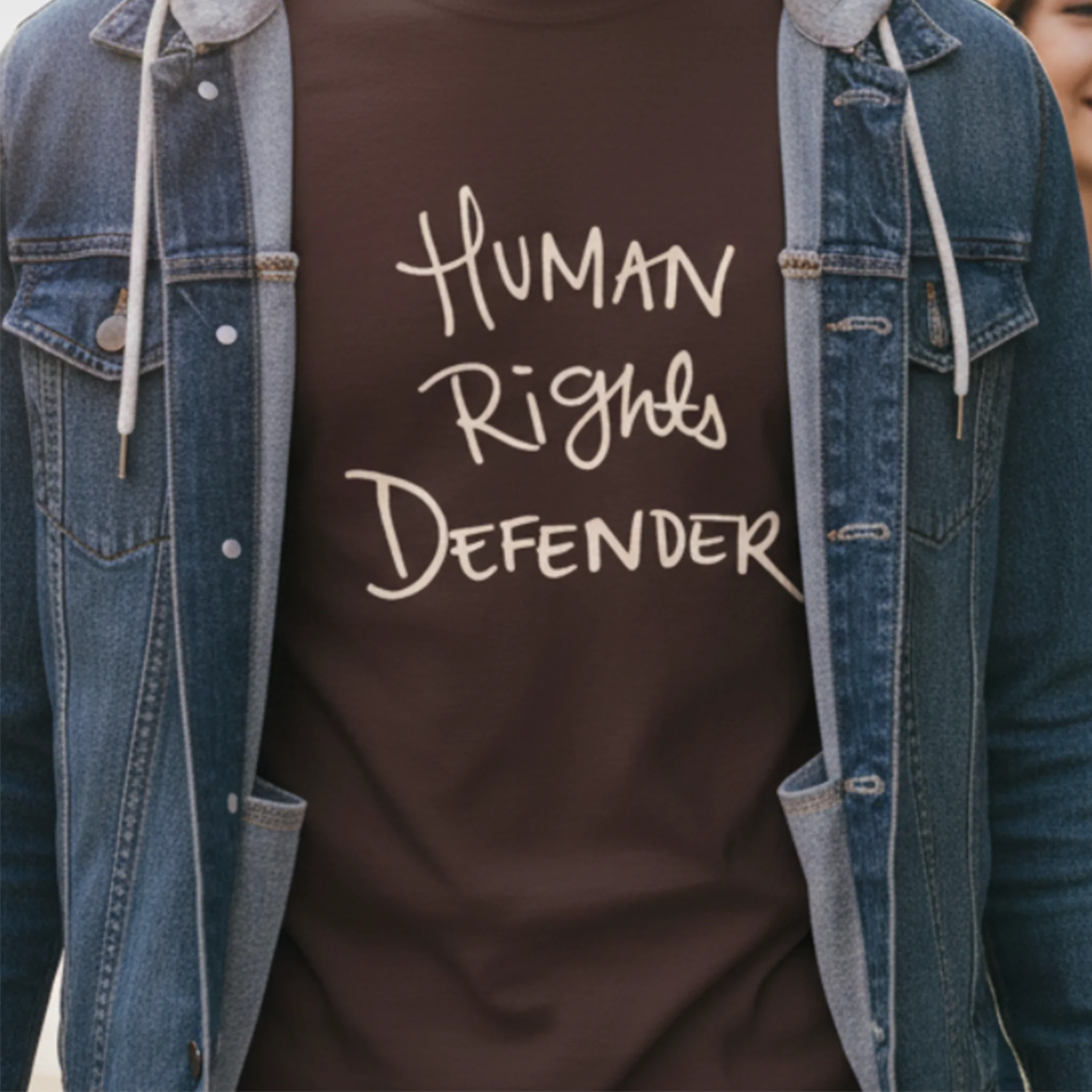 Dark Chocolate Human Rights Defender long sleeve tee styled with denim jacket, cream graphic, street lifestyle front view.