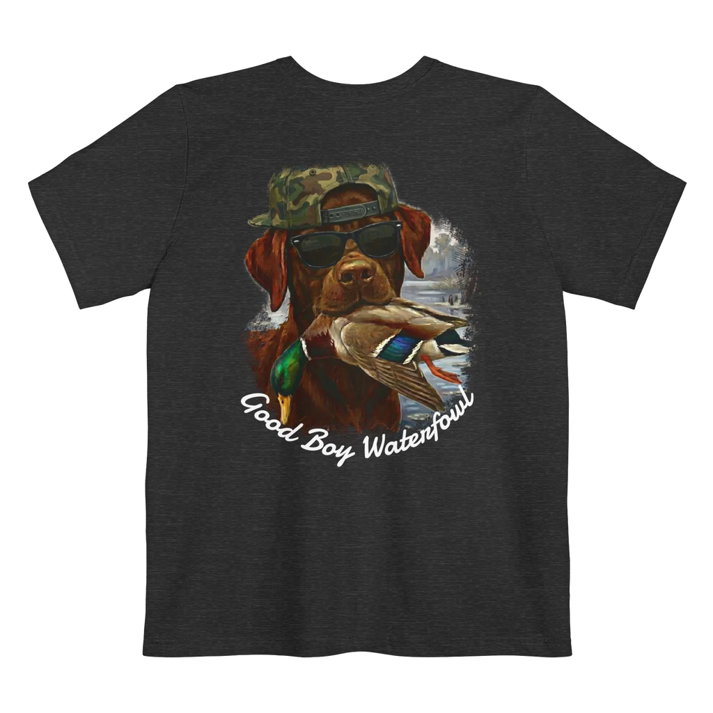 A dark grey heather t-shirt featuring the Good Boy Waterfowl graphic of a chocolate Labrador wearing sunglasses and a camo snapback, holding a mallard duck, with a watercolor outdoor scene and 'Good Boy Waterfowl' script below.