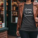 Dark Heather Human Rights Defender long sleeve tee styled with leather jacket, white graphic, street lifestyle front view.