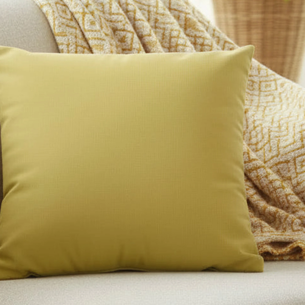 Dull gold yellow faux suede pillow case styled on a couch in a modern living room.