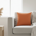 Dusty orange faux suede throw pillow styled on a couch in a warm earthy living room.