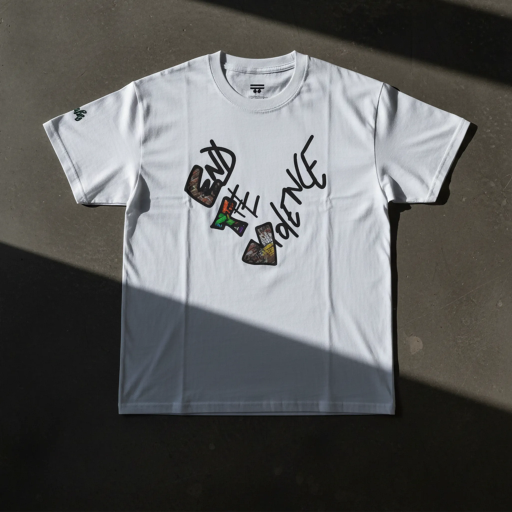 Graphic heart t-shirt with graffiti-style "End the Violence" mixed-media art, white, flat lay on dark concrete surface