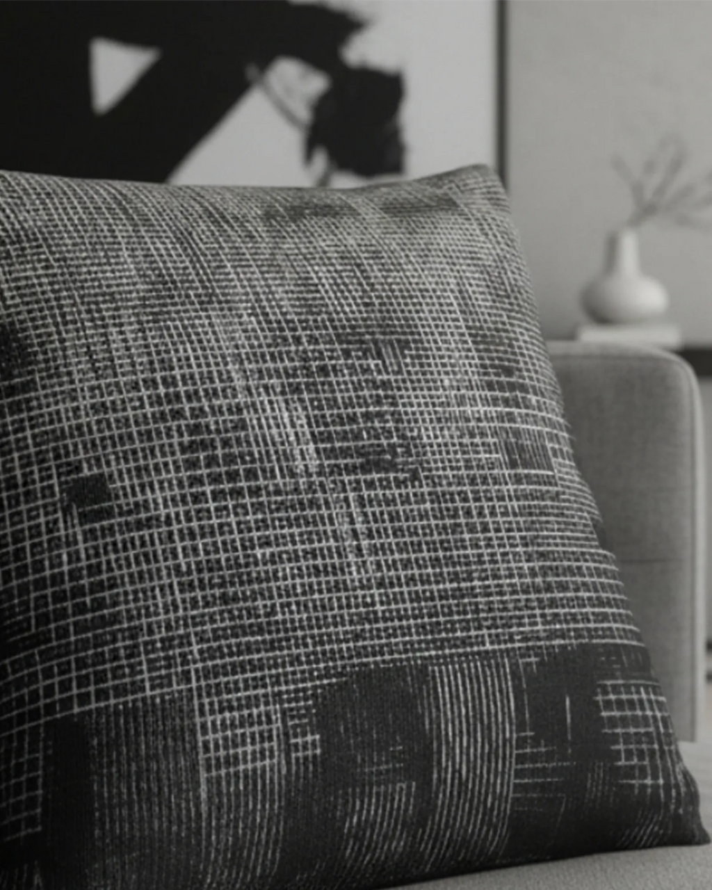 Grey modern sofa in a minimalist living room with black abstract wall art and a white ceramic vase styled with the Faded Geometric Woven Pillow.
