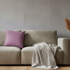 Faded lilac faux suede throw pillow styled on a couch in a calm nordic soft-brutalist living room.