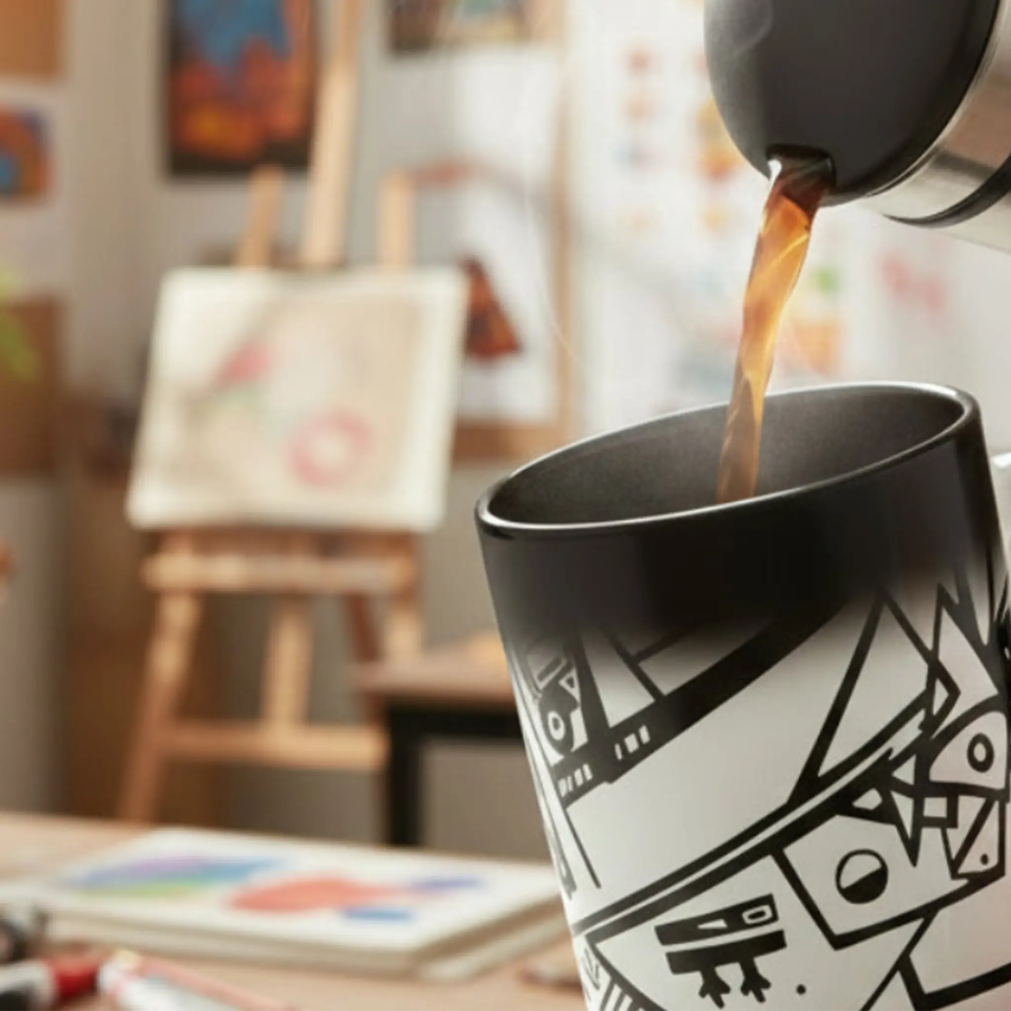 Coffee being poured into Freebrd Ecliptic heat changing mug revealing hidden line art design in artist's studio.