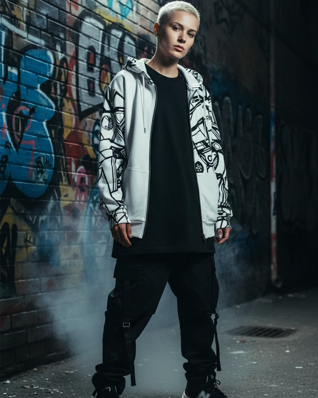 Person wearing an ‘Ecliptic’ Freebrd full-zip hoodie in an urban editorial setting with a graffiti wall backdrop and moody city lighting for a bold bold black-and-white abstract art vibe.