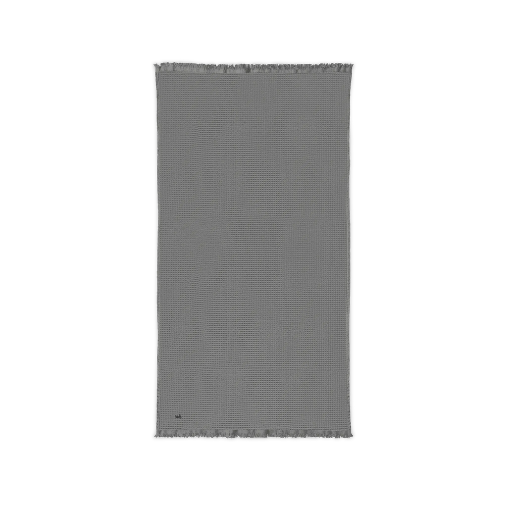 Gusty Grey cotton waffle throw blanket laid flat, showing its textured surface and fringed ends.