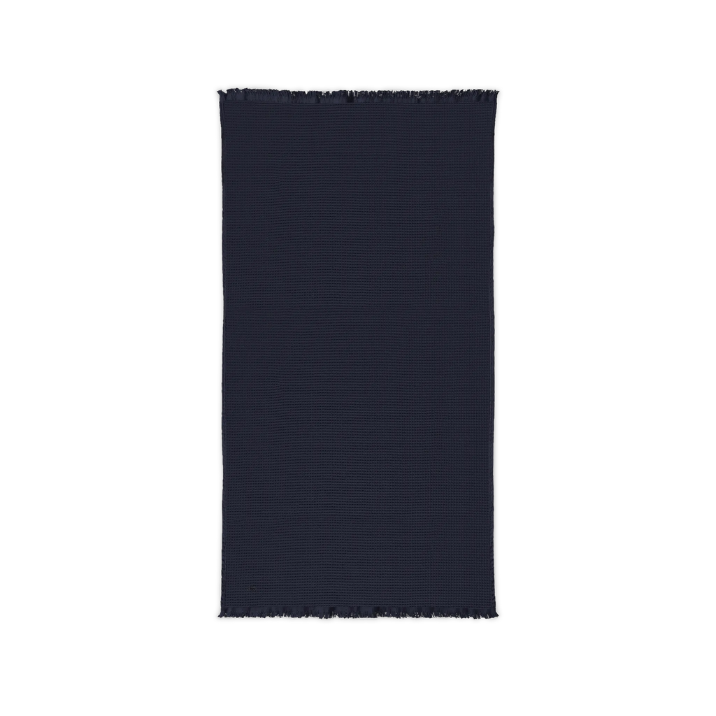 River Blue Navy cotton waffle throw blanket laid flat, showing its textured surface and fringed ends.
