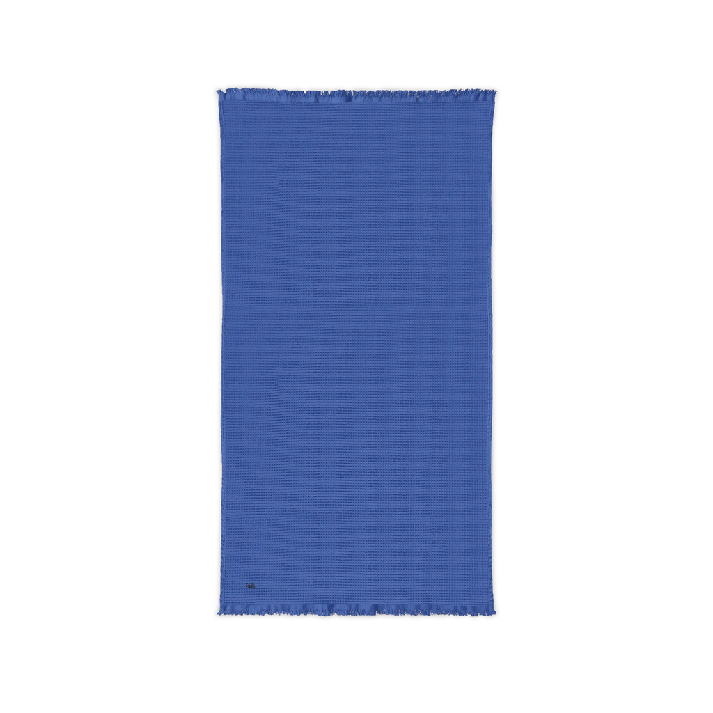 Ultramarine blue cotton waffle throw blanket laid flat, showing its textured surface and fringed ends.