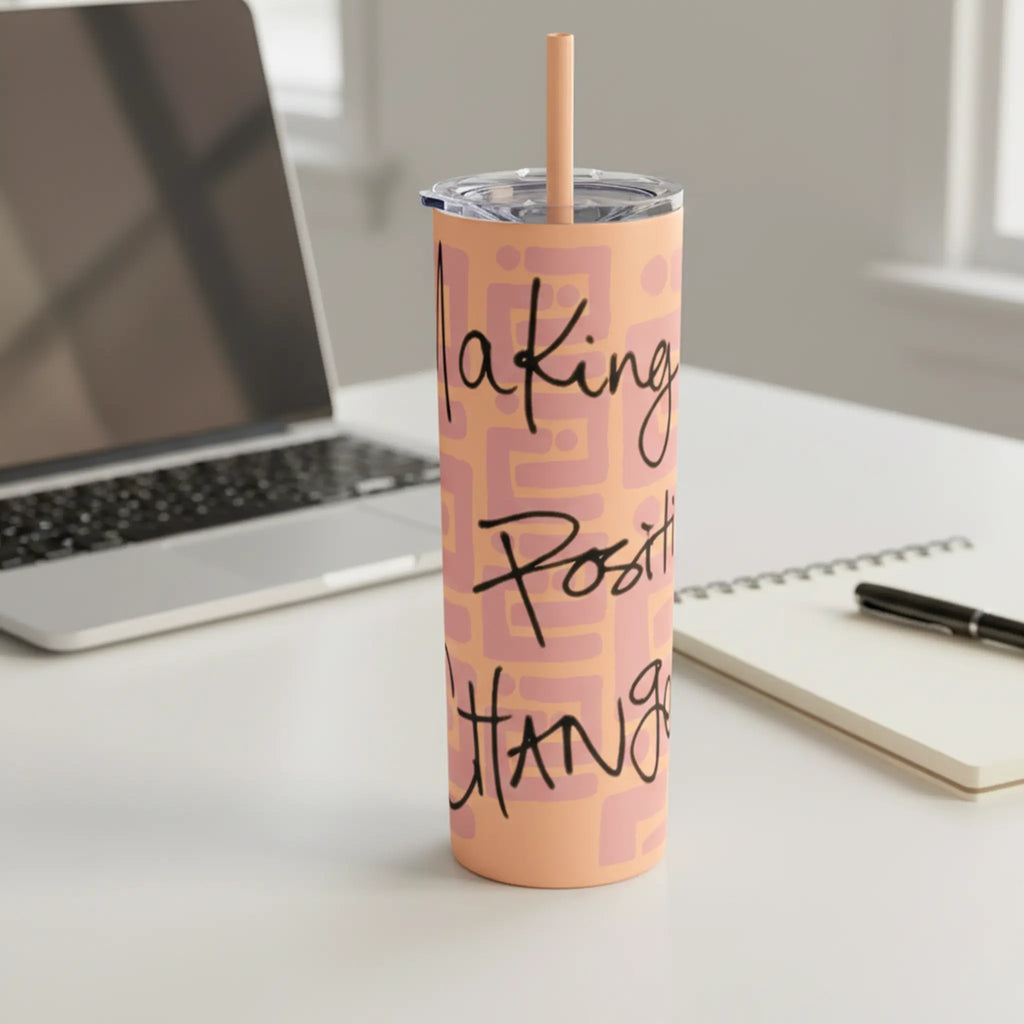 Freebrd Making Positive Changes 20oz peach blush skinny tumbler with black script text sitting on a clean modern work desk with soft natural light and laptop in background.