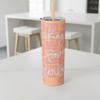 Freebrd Making Positive Changes peach blush skinny tumbler with white glitter script text on a bright white kitchen island in a clean airy kitchen setting.