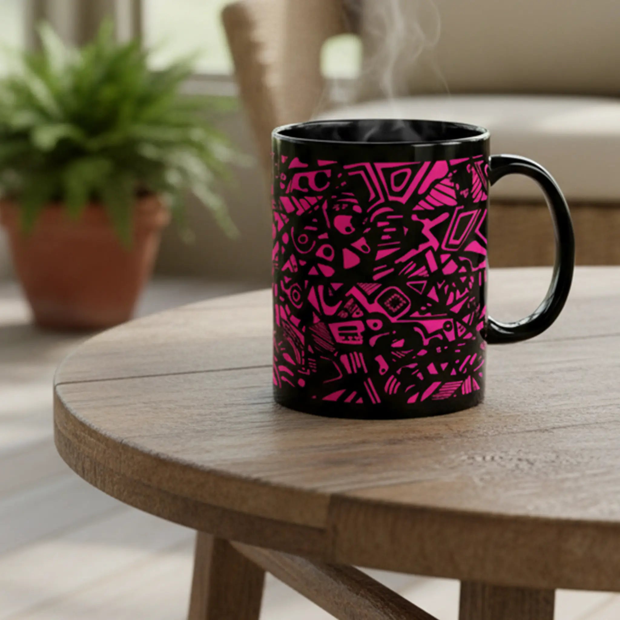 Freebrd Medicolo neon pink abstract black ceramic mug sitting on a cozy indoor patio table with soft natural daylight and warm, southern indoor patio setting in the background.
