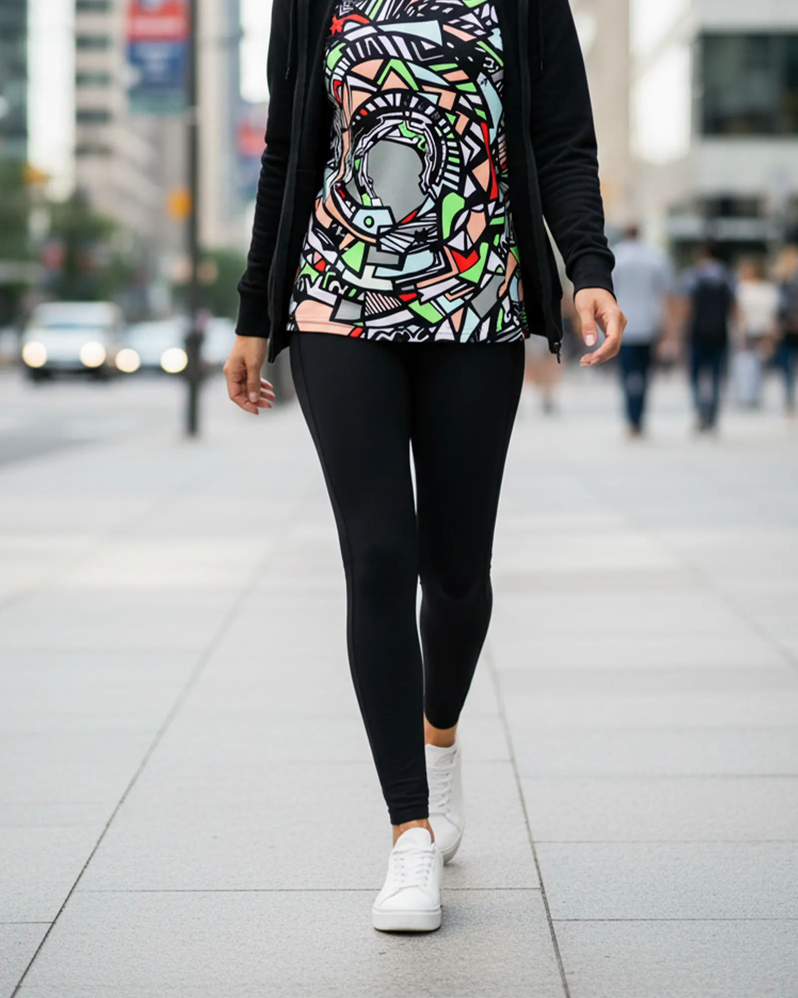 Person wearing a colorful FREEBRD unique ‘Zonch’ fashion top graphic t-shirt and black jeggings walking on a city street.