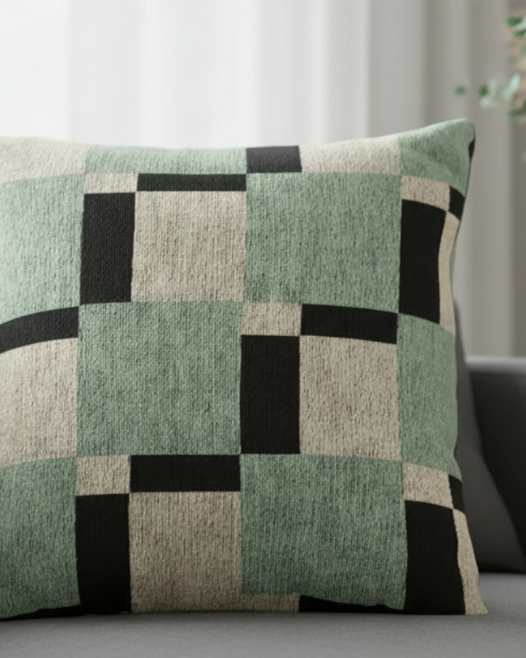 Dark charcoal sofa in a bright modern living room with sheer white curtains and a eucalyptus stem styled with the Fresh Green Carbon Floater Checker Woven Pillow.
