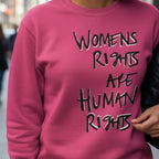 Hot Pink Women's Rights sweatshirt, handwritten Womens Rights Are Human Rights graphic, crew neck, close-up graphic detail, city street lifestyle front view.