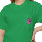A person wearing a FREEBRD Irish green classic cotton pocket t-shirt with a baby pink cartoon finger-snap Clock It graphic printed on the front chest pocket.